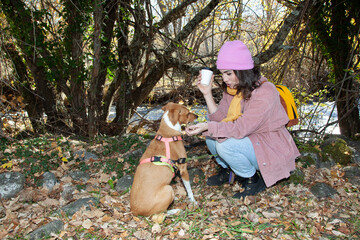 niña sentada en el campo con su perro. Mujer de excursión con su perro. mujer con cafe