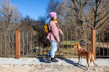 Mujer en puente con su perro. Mujer vestida de rosa en la montaña. Estilo de vida. Excursión en la montaña