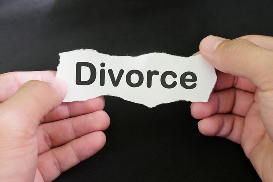 Divorce concept. Hand holding a piece of paper with written divorce on black background.