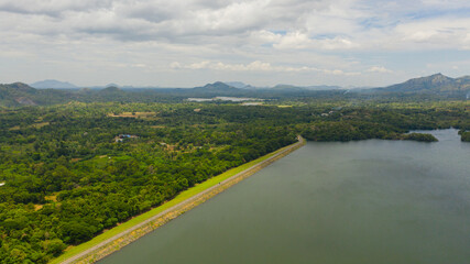 Highway along the lake surrounded by jungle and rainforest. Loggal Oya Reservoir. Sri Lanka.