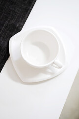 Empty white tea cup and saucer on the table. Porcelain dishes, selective focus.