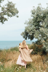 Blond beautiful Mother with her son go to ocean back view