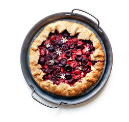 Summer strawberry cherry galette pie on a tin plate isolated on white