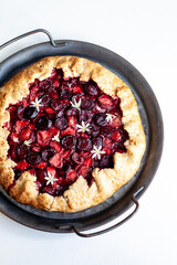 Summer strawberry cherry galette pie on a tin plate isolated on white