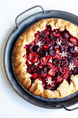 Summer strawberry cherry galette pie on a tin plate isolated on white
