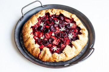 Summer strawberry cherry galette pie on a tin plate isolated on white