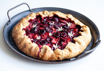 Summer strawberry cherry galette pie on a tin plate isolated on white