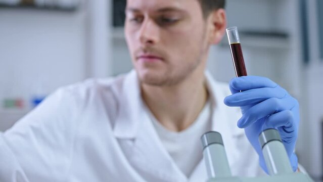 Diagnostic laboratory scientist examining infected blood sample under microscope