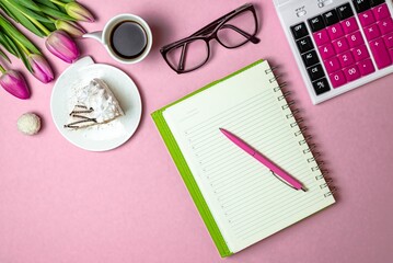 Flat lay view of desktop surface, tulips, coffee with cake and notepad with calculator on pink light background, holiday in financial sphere
