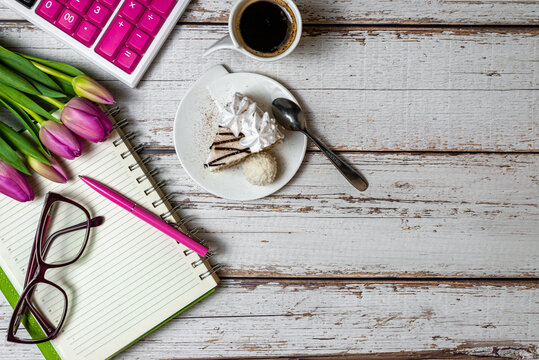 Flat lay view of desktop surface tulips coffee with cake and notepad with calculator on wooden light background,, holiday in financial sphere