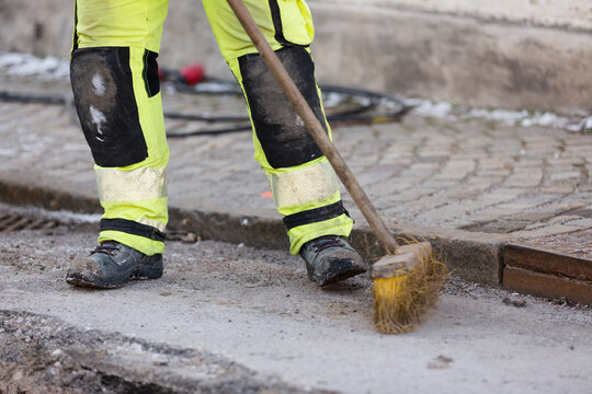 Worker in reflective clothing sweeping street