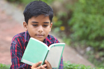 Indian schoolboy  reading a book in the garden