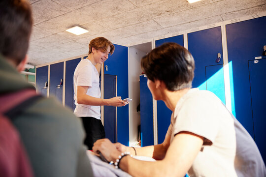 Teenage boys using cell phone in locker room