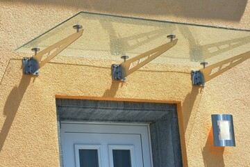 Rahmenloses Glas-Vordach, abgehängt an Edelstahl-Streben, an einem Wohnhaus