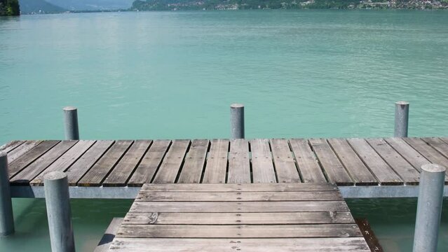 Beautiful view from the wooden pier to the lake on a sunny summer day, Brienz lake with clear turquoise water. Brienz lake in the village of Iseltwald, Switzerland