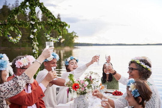 Family raising toast during midsummer dinner by lake