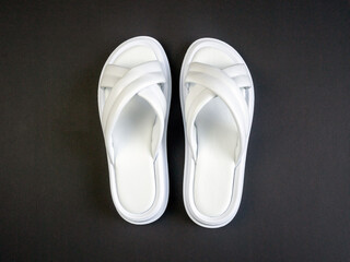 Women's summer white slippers on a black background. Slippers. Horizontal image