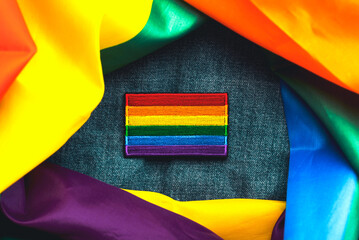 Close-up of LGTBI flag textile patch on a denim jacket and LGTBI flag. Pride day concept
