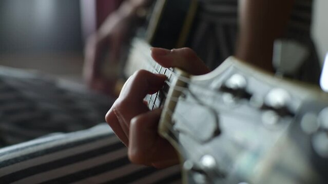 Close-up hands of unrecognizable little girl playing chords on guitar, learning using electric guitar for music self studying at home. Closeup of kid girl practicing to play the musical instrument.