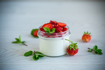 Sweet homemade yogurt with fresh ripe strawberries in a glass jar