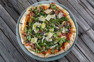 Sliced pizza with meat jamon and arugula. Sprinkled with Parmesan cheese.