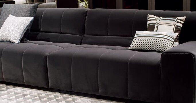 Modern dark gray fabric sofa. Textile upholstery sofa with pillows. Modern apartment beautiful dark gray fabric sofa in minimalist living room with table. Gray modern Sofa in minimalist room.