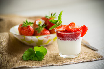 sweet homemade yogurt with strawberry jam and fresh strawberries in a glass cup