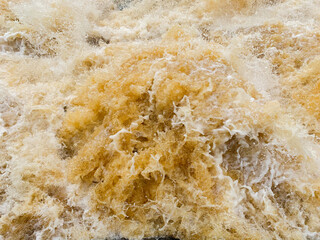 Yellow orange foaming stream of water with splashes. High quality photo