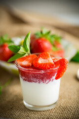 sweet homemade yogurt with strawberry jam and fresh strawberries in a glass cup