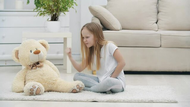 4k video of small girl arguing with her teddy bear.