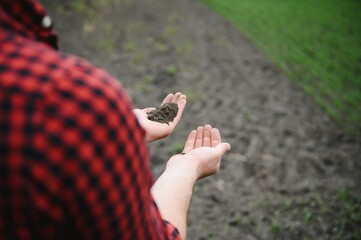 Farmer's hands hold a handful of fertile soil. The concept of agriculture, agribusiness. The gardener holds humus, fertilized soil, compost soil in his palms. Agriculture and fertility.