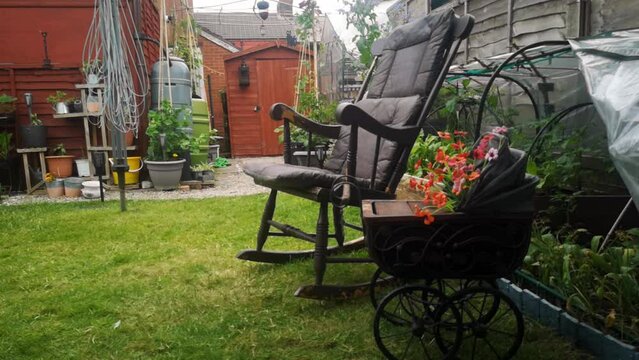 Rustic rocking chair and spooky gothic wooden pram planter in peaceful idyllic English garden shade