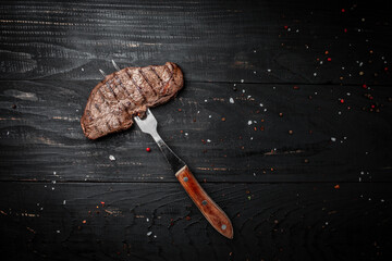 Rump Steak on fork on dark wooden background. banner, menu recipe place for text, top view