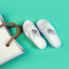 Women's summer white slippers and a white rubber bag with brown handles on a black background. Slippers. Square image