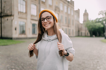 Happy caucasian female student walking around the campus smiling at the camera.