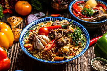 Traditional uzbek meal called pilaf. Rice with meat on plate with oriental ornament on a dark wooden background, Long banner format. space for text