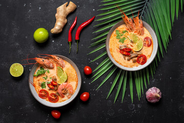 Tom Yum kung Spicy Thai soup with shrimp in a bowls on a black stone background. View from above
