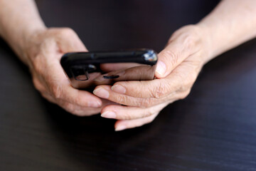Elderly woman with smartphone, mobile phone in wrinkled female hands close up. Concept of online communication in retirement, ambulance call