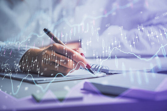 Double exposure of woman's hands making notes with forex graph hologram. Concept stock market analysis.
