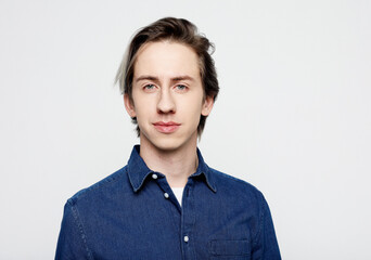 Young man wear blue denim shirt looking at camera on grey background