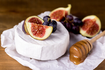 Gourmet Appetizer White Brie Cheese or Camembert with Fresh Figs Honey and Grape Wooden Background Horizontal