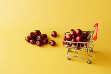 Fresh red cherries in a metal trolley from a supermarket. The concept of buying berries and fruits in the store. Yellow background.