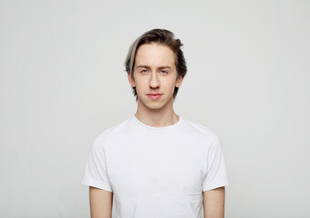 young man wear white t-shirt looking at camera on grey background