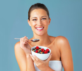 Healthiness and happiness go hand in hand. Studio shot of an attractive young woman eating a bowl...