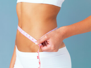 The proof is in the inches. Cropped studio shot of a fit young woman measuring her waist against a...