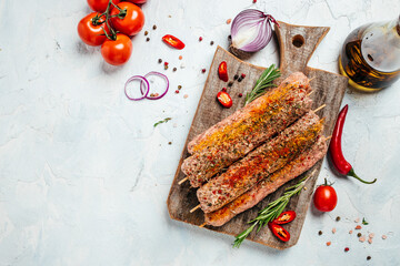 raw Lula kebab on skewers with spices on a cutting board light background. Lula kebab, traditional...