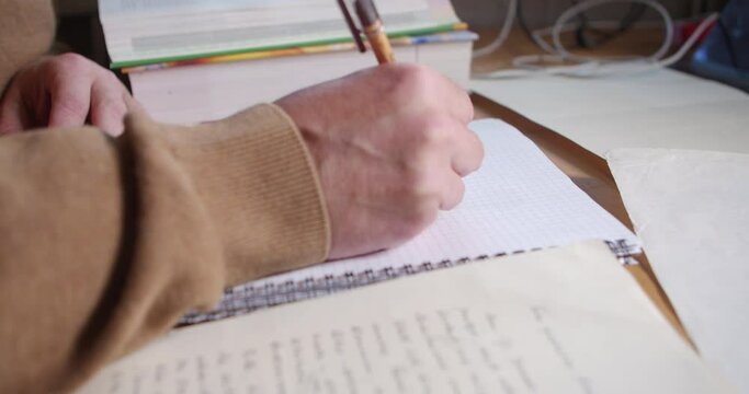 The person is taking notes and looking at documents. Close-up shot.