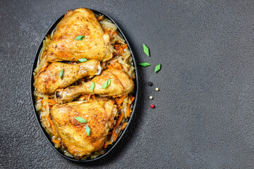 Spicy roasted chicken with vegetables on dark background. Space for text, top view.