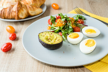 Healthy breakfast. Eggs, vegetable salad and avocado, croissants and a bun. Diet breakfast, balanced diet. top view
