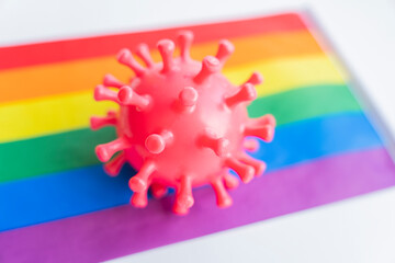 rubber virus lies on the rainbow flag. The concept of the risk of contracting a virus